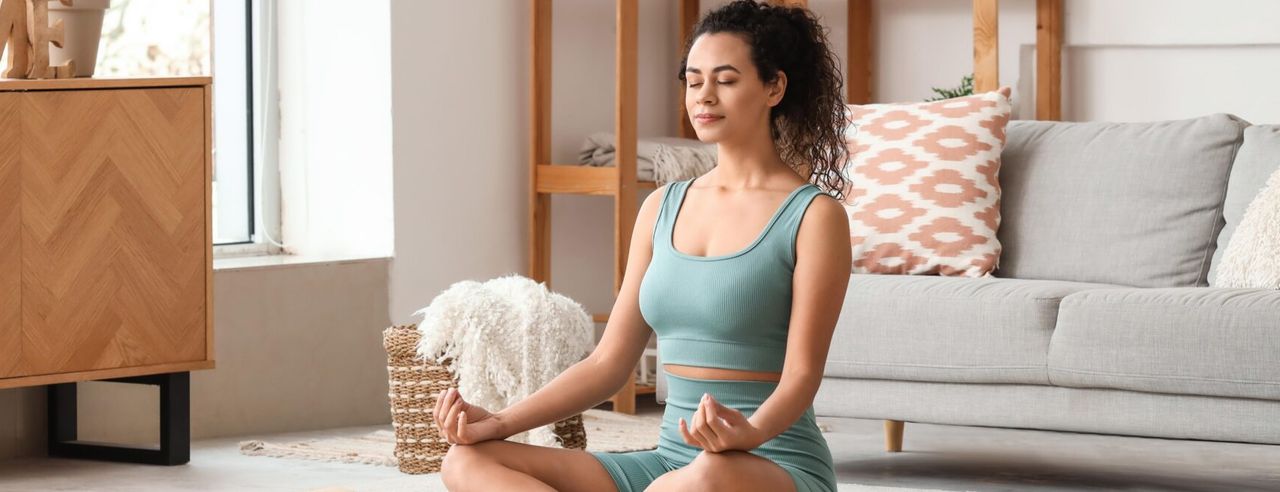 Eine Frau meditiert im Wohnzimmer
