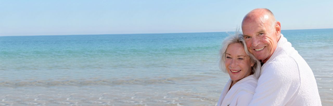 Älteres Paar umarmt sich glücklich am Strand
