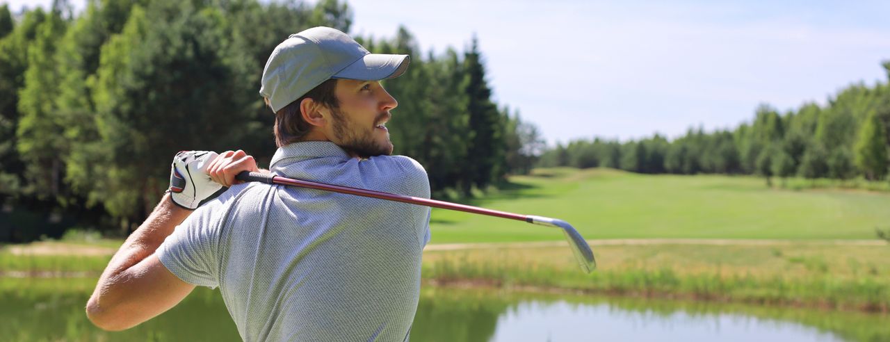 Ein Mann beim Abschlag auf dem Golfplatz