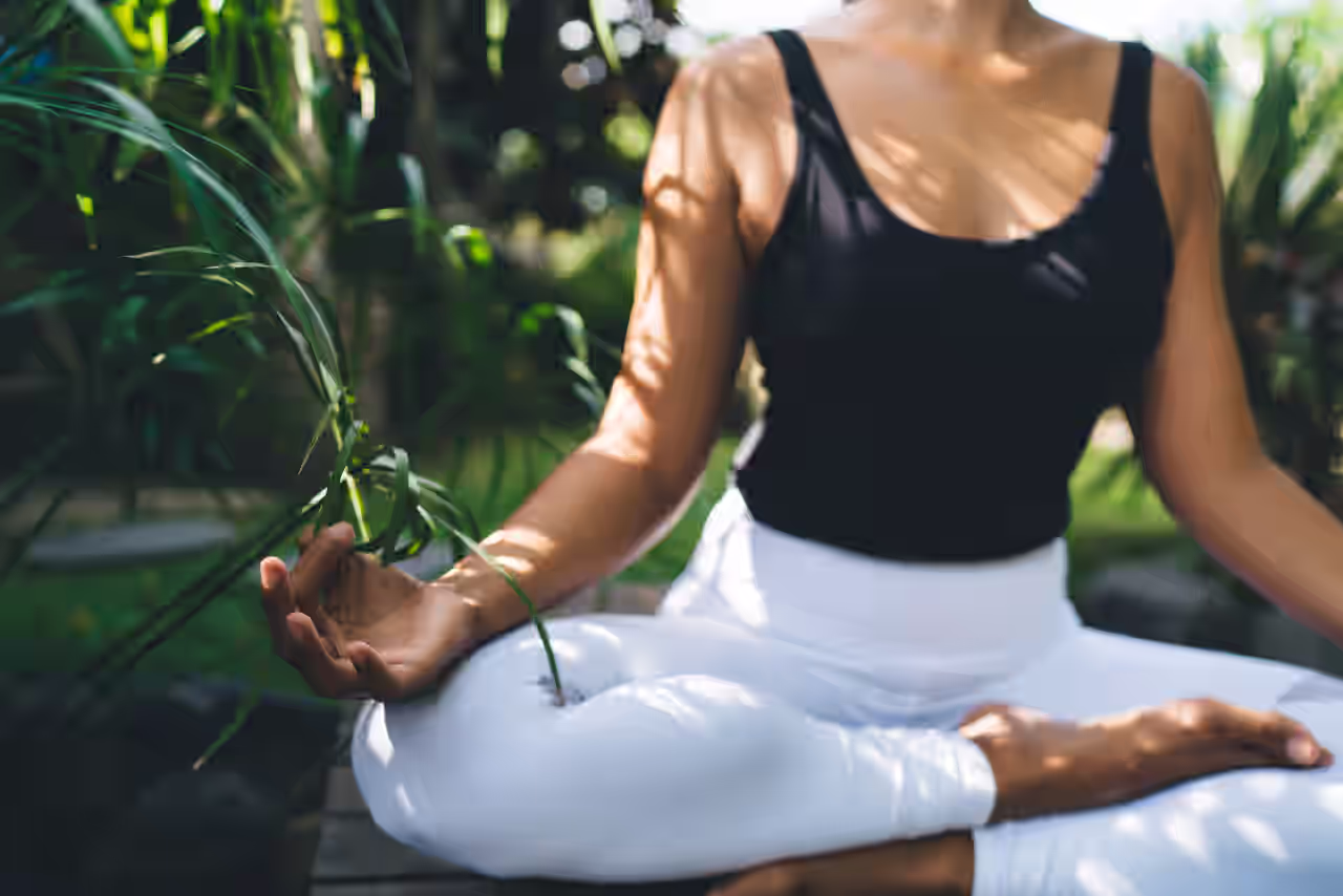 Eine Frau in Meditationspose in einem tropischen Garten bei ihrer spirituellen Reise auf Bali