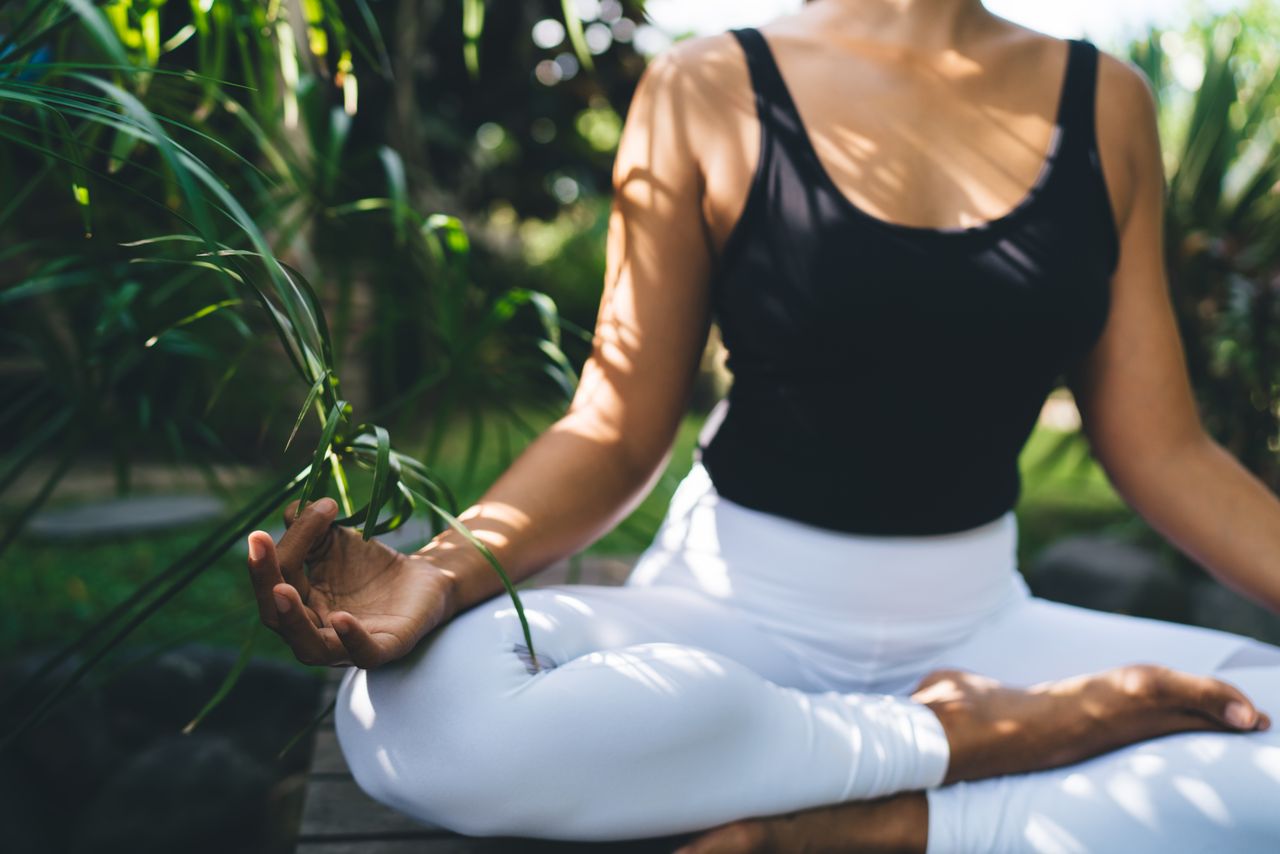 Eine Frau in Meditationspose in einem tropischen Garten bei ihrer spirituellen Reise auf Bali