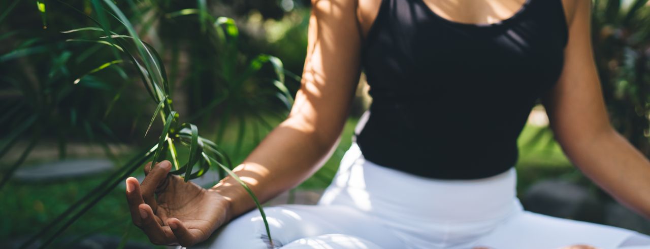 Eine Frau in Meditationspose in einem tropischen Garten bei ihrer spirituellen Reise auf Bali