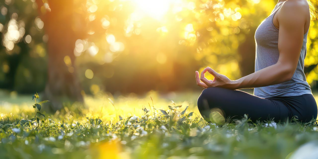 Eine Frau praktiziert Yoga auf einer schönen Wiese in Oberstaufen in Ihrem Yoga Urlaub