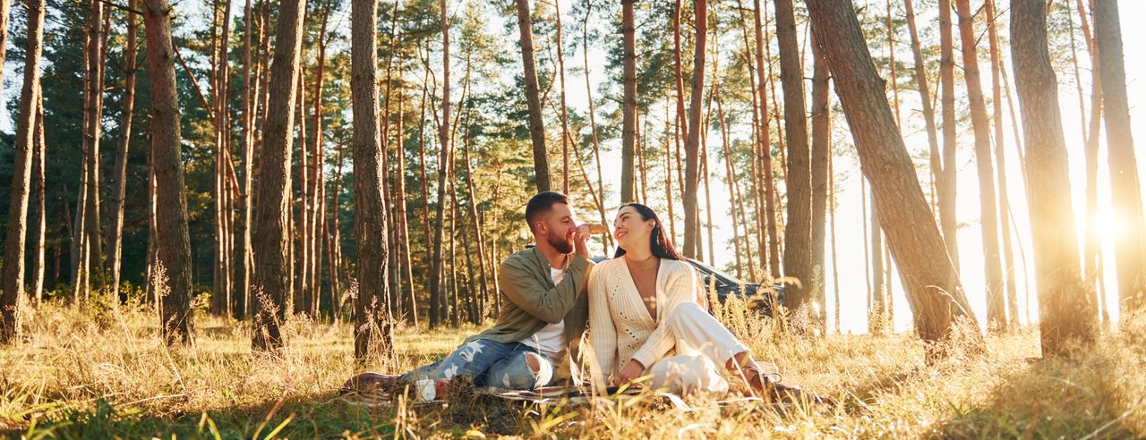 Mann und Frau sitzen bei Sonnenschein im Wald