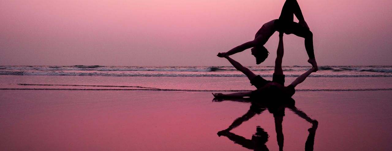 Zwei Menschen am Strand beim Acro Yoga