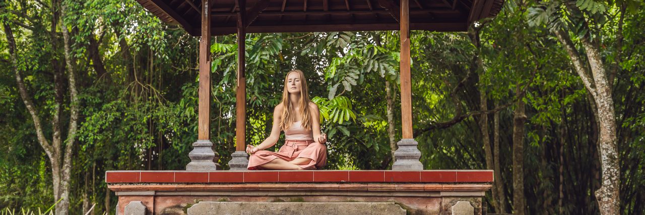 Eine Frau meditiert an einem Schrein in Thailand