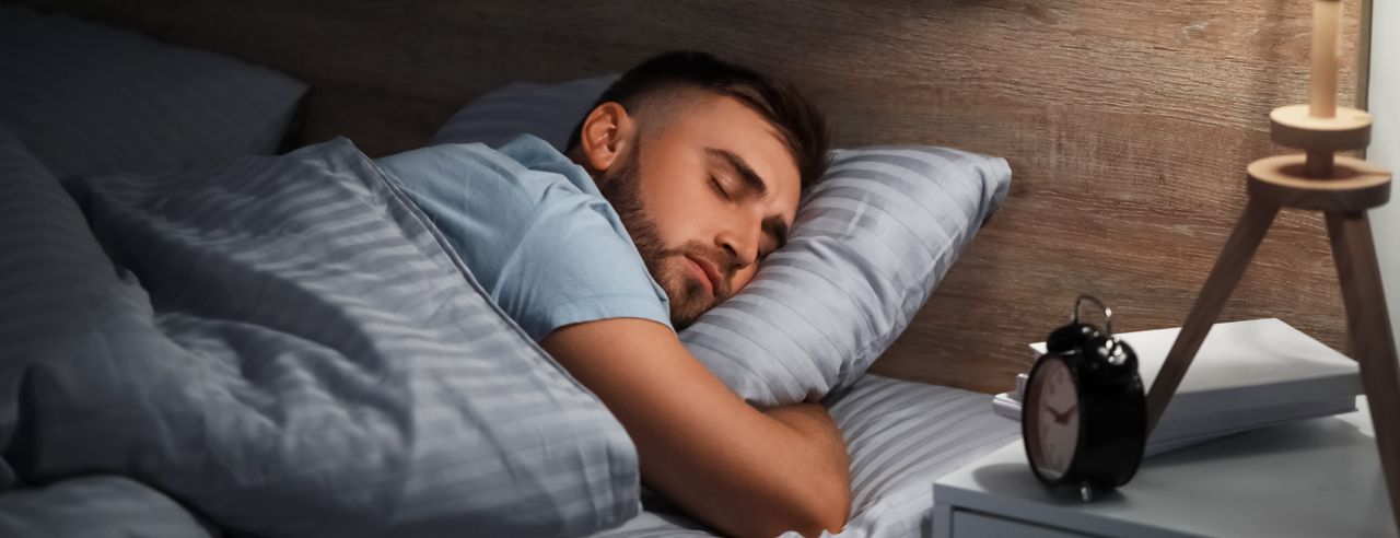 A young man sleeps in his bed