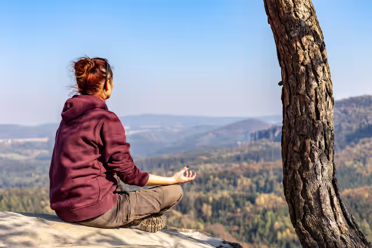 Wandererin meditiert mit Blick über die Berge