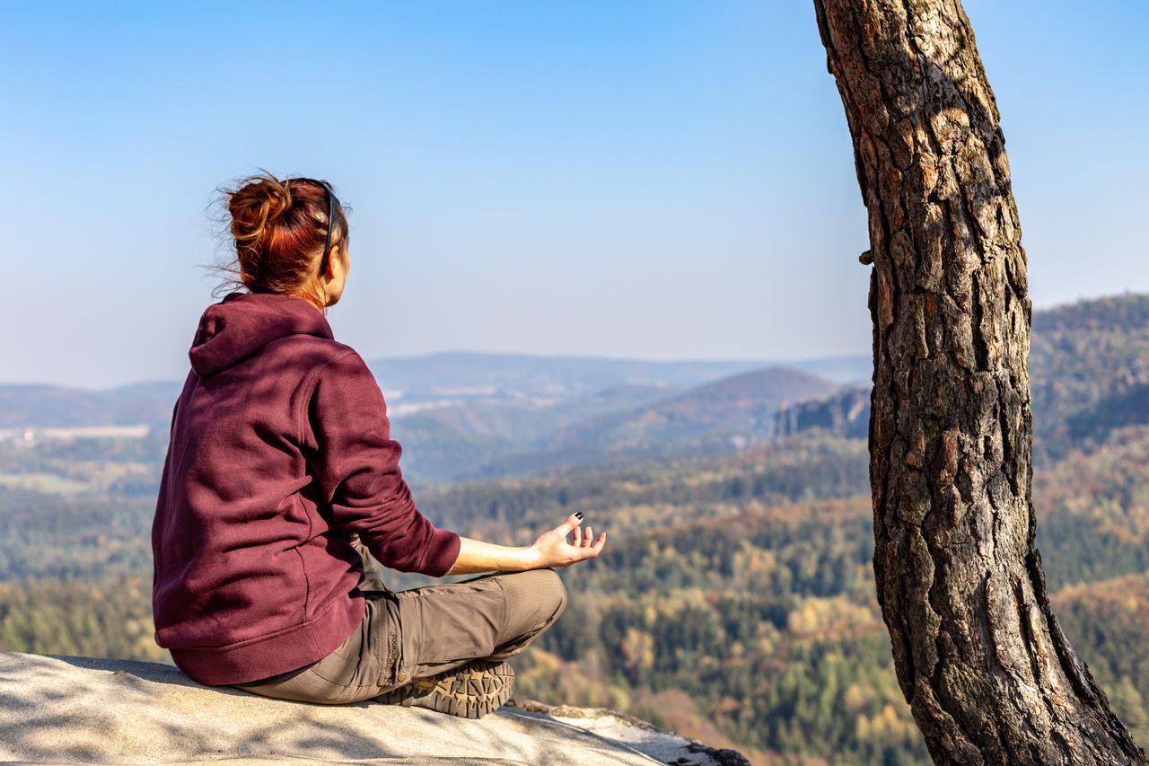 Wandererin meditiert mit Blick über die Berge