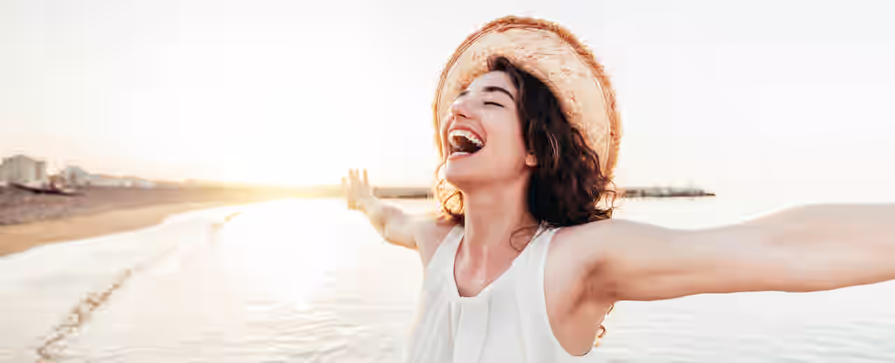 Eine fröhliche Frau am Strand mit ausgebreiteten Armen