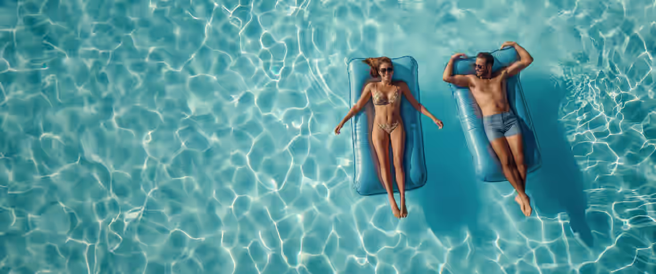 Ein Paar relaxt im Pool auf Luftmatratzen in ihren Flitterwochen in Spanien