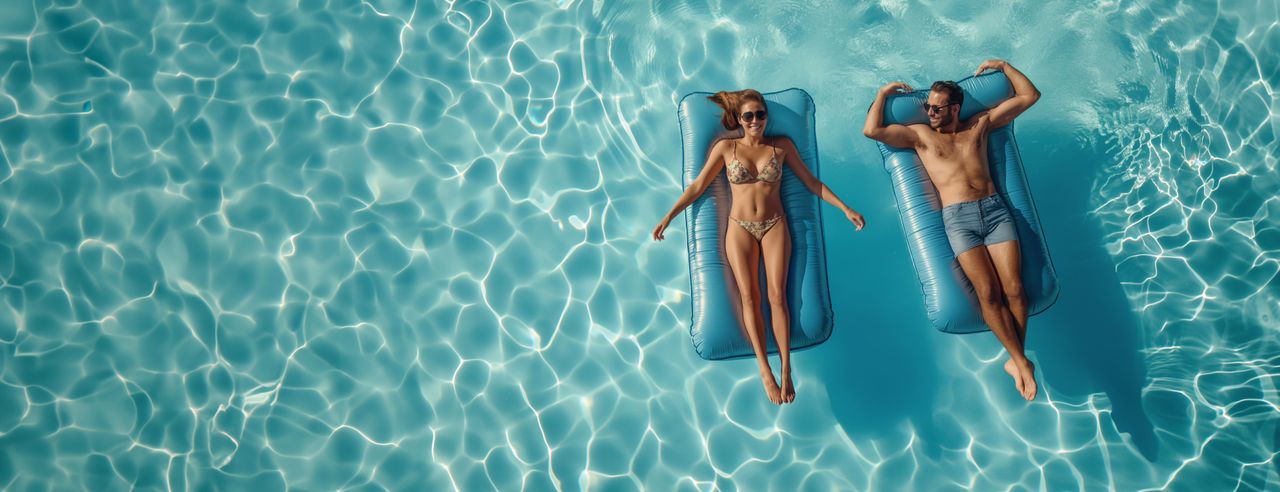 Ein Paar relaxt im Pool auf Luftmatratzen in ihren Flitterwochen in Spanien