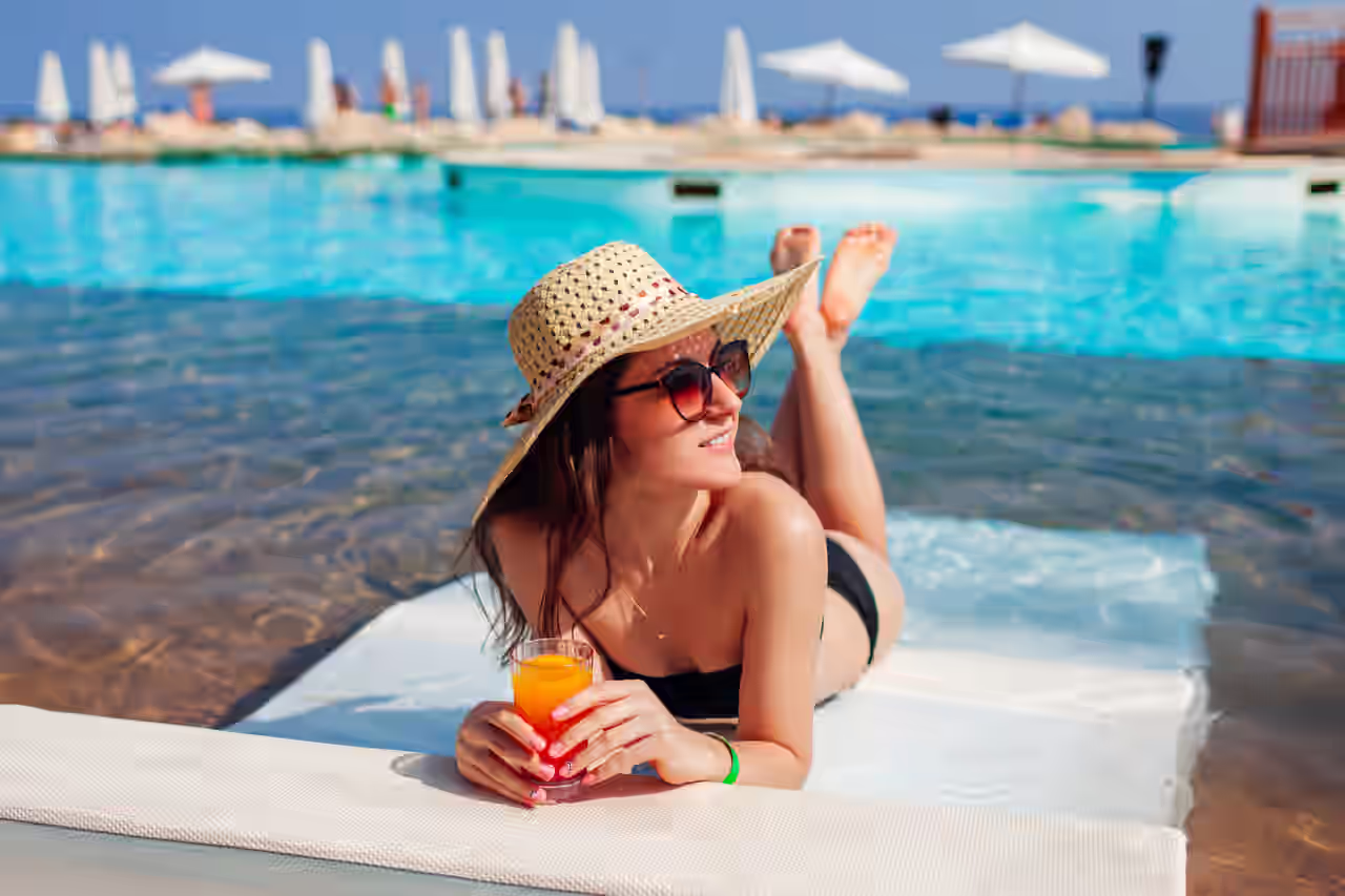 Eine Frau mit Cocktail liegt auf einer Liege im Wasser