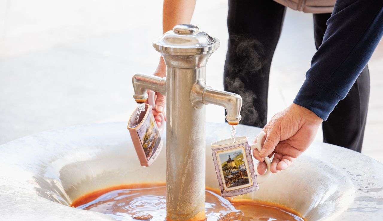 Menschen, die ihren Becher mit Heilwasser befüllen