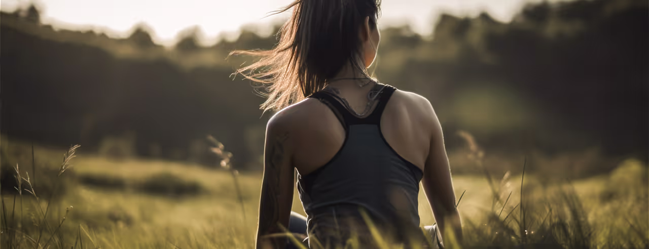Une femme assise sur une prairie en pleine conscience pour prévenir le stress et le burnout