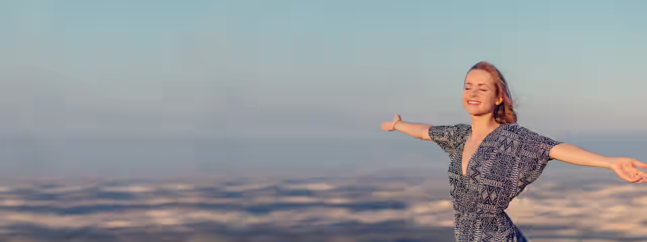 Eine fröhliche Frau Breitet die Arme aus vor einem Natur-Panorama