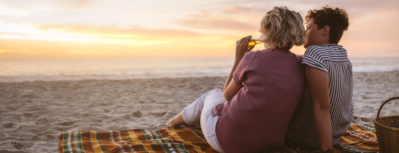 Zwei Frauen sitzen am Strand und machen ein Picknick