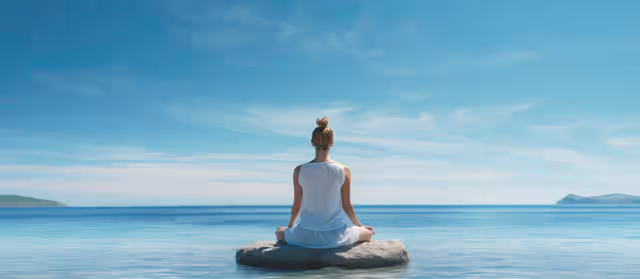 Eine Frau übt Ihre Yoga Asanas am Strand von Zypern. Sie sitzt auf einem Stein im Wasser und der Himmel strahlt schön blau.
