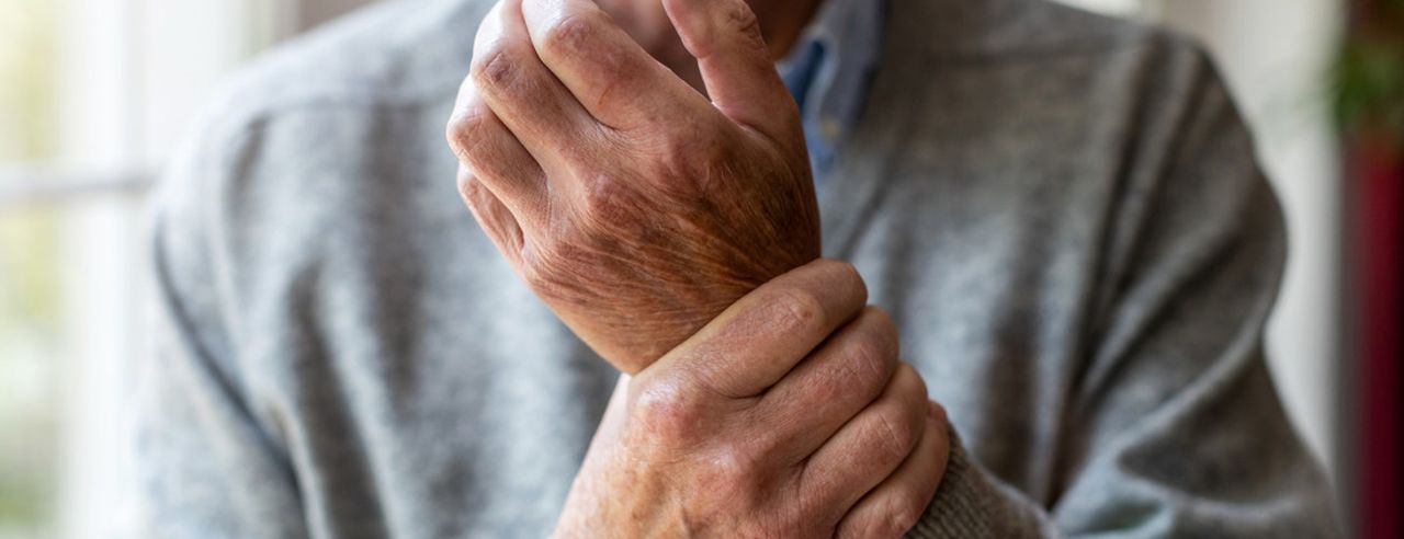 Ein älterer Herr fasst sich ans Handgelenk