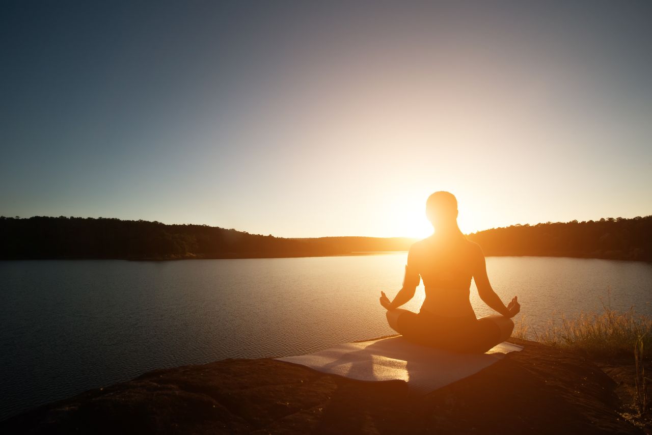 Eine Frau bei Sonnenaufgang beim Vini Yoga
