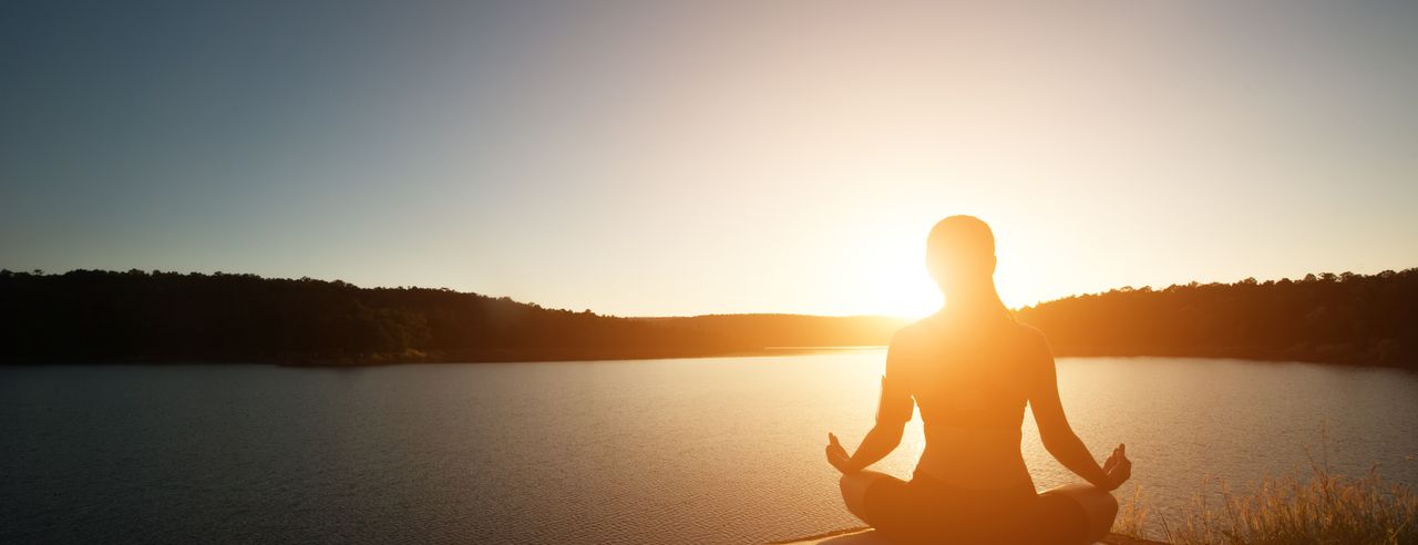 Eine Frau bei Sonnenaufgang beim Vini Yoga