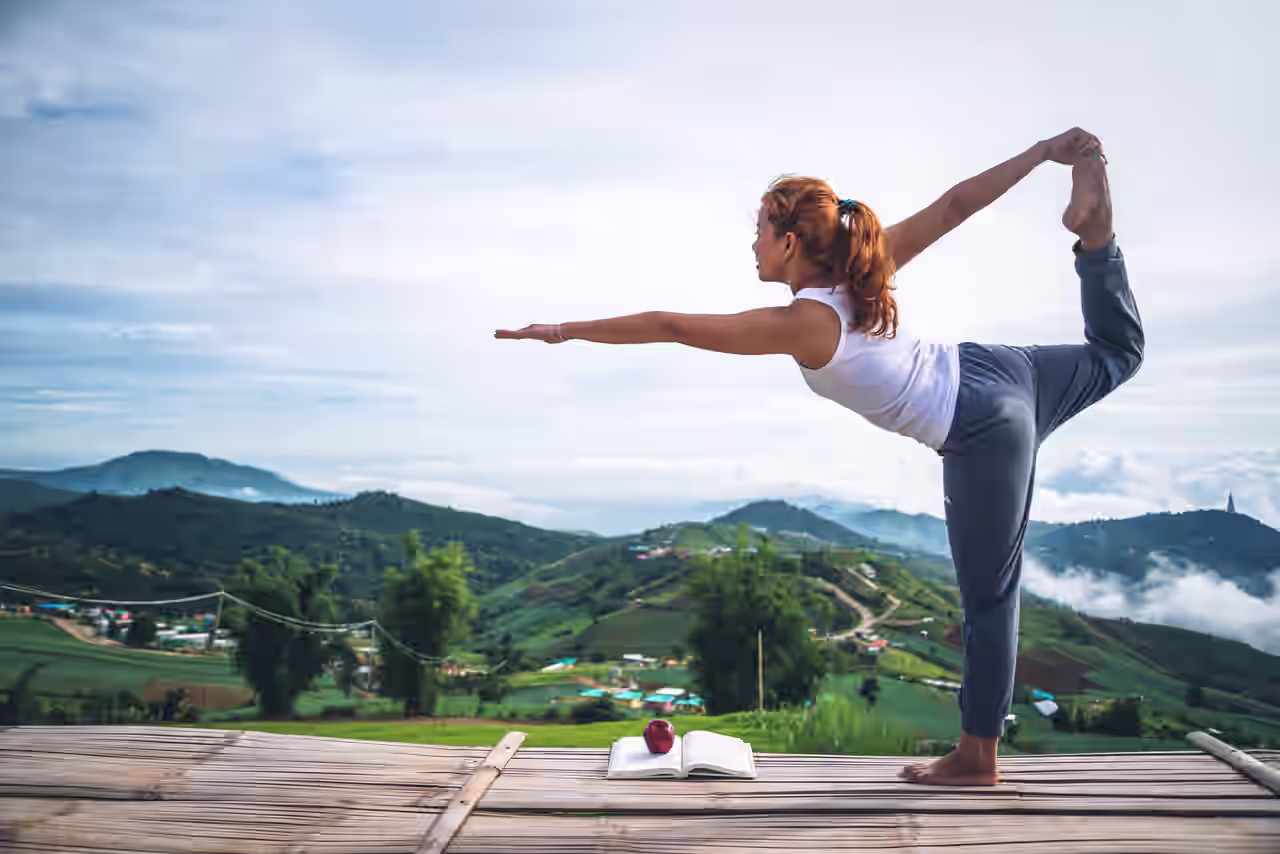 Frau sitzt im Schneidersitz in einer tropischen Umgebung, sie macht Yoga in Asien