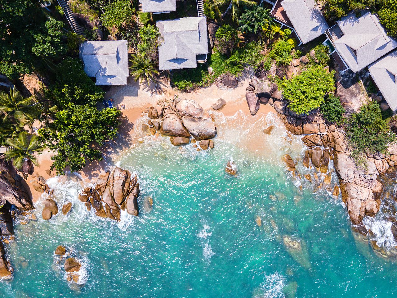 Blick von oben auf Bungalows im Regenwald am Strand