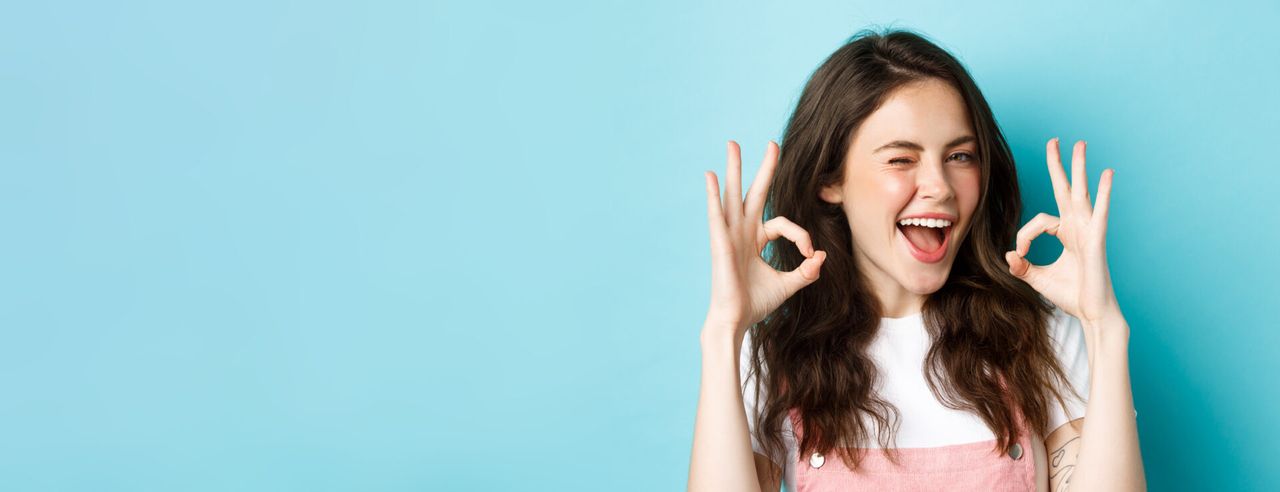 Eine Frau macht das Ok-Zeichen und lächelt, weil sie durch Akupunktur abgenommen hat