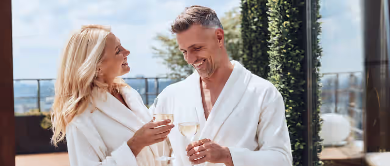 Ein Paar mit Weingläsern auf der Terrasse eines Hotels mit Panoramablick