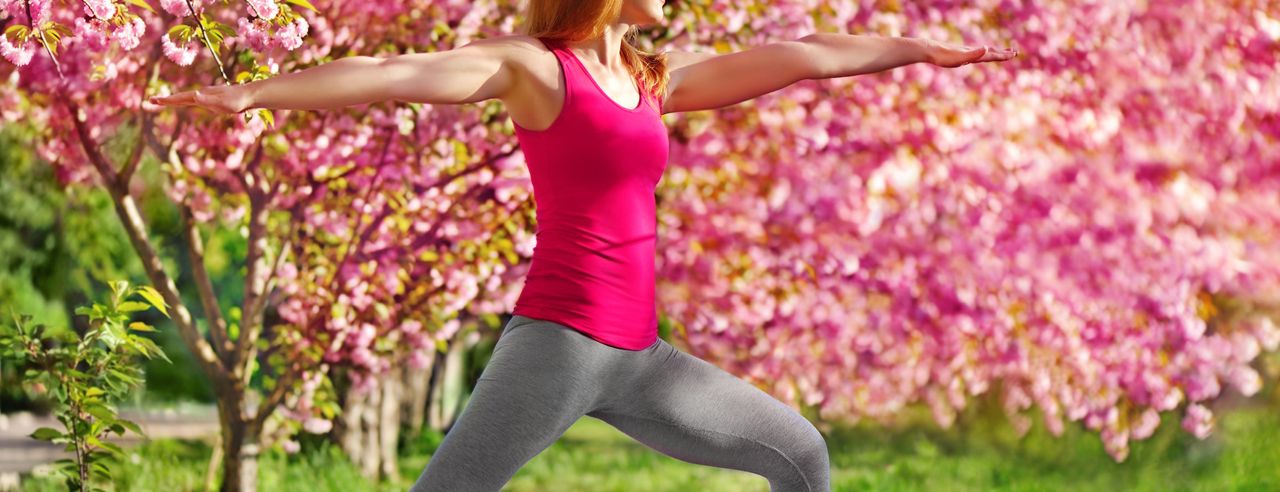 Frau macht Yoga zwischen blühenden Bäumen