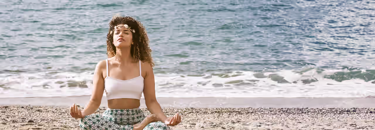 Eine Frau meditiert am Strand