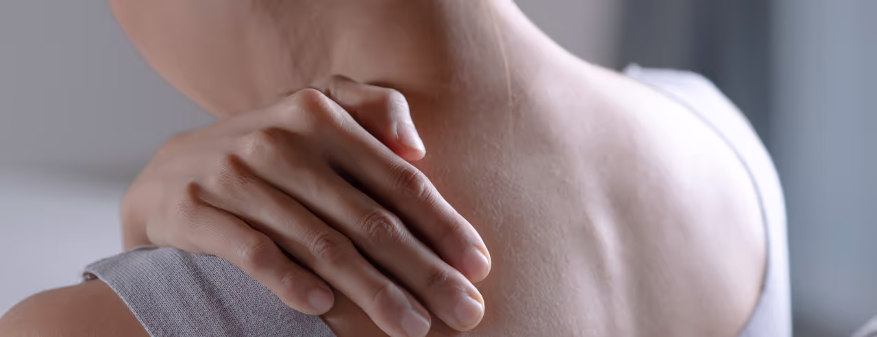 Une femme se tient l'épaule douloureuse