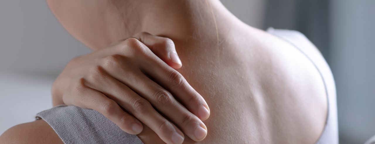 Una donna si tiene la spalla dolorante