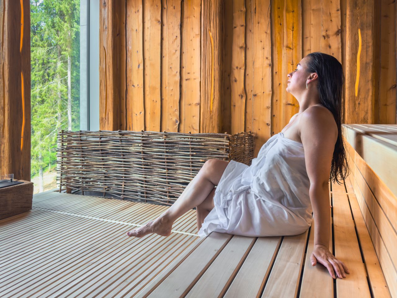 Eine Frau entspannt in der Sauna mit Waldblick