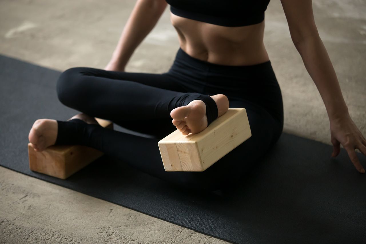 Eine übt Iyengar Yoga mit Klötzen an den Füßen