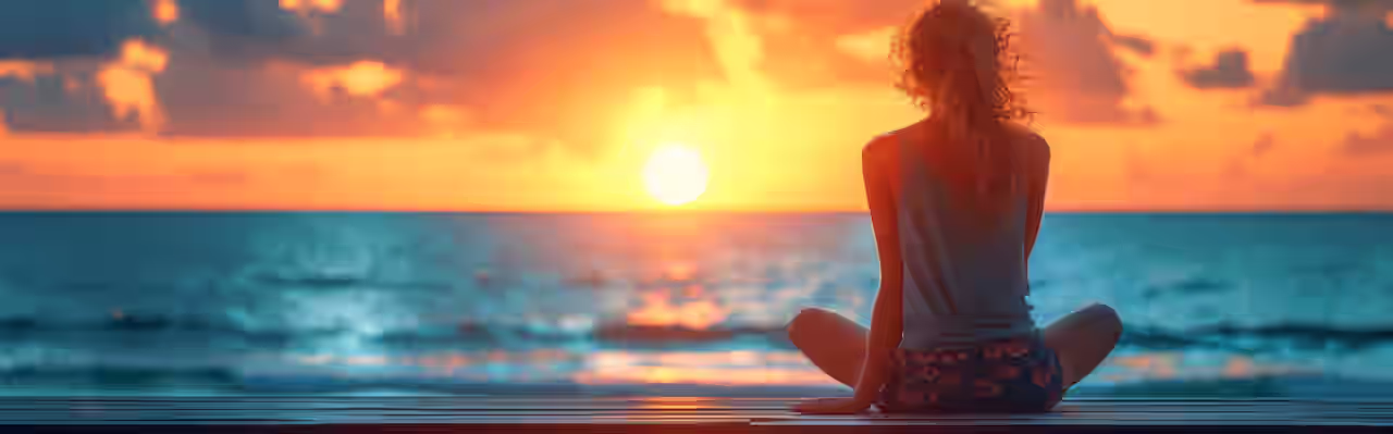 Eine Frau sitzt in Yoga Pose am Meer