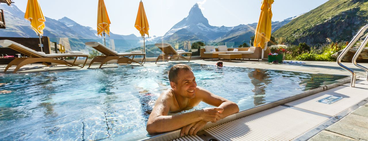 Ein Mann im Außenpool eines Hotels mit Bergblick