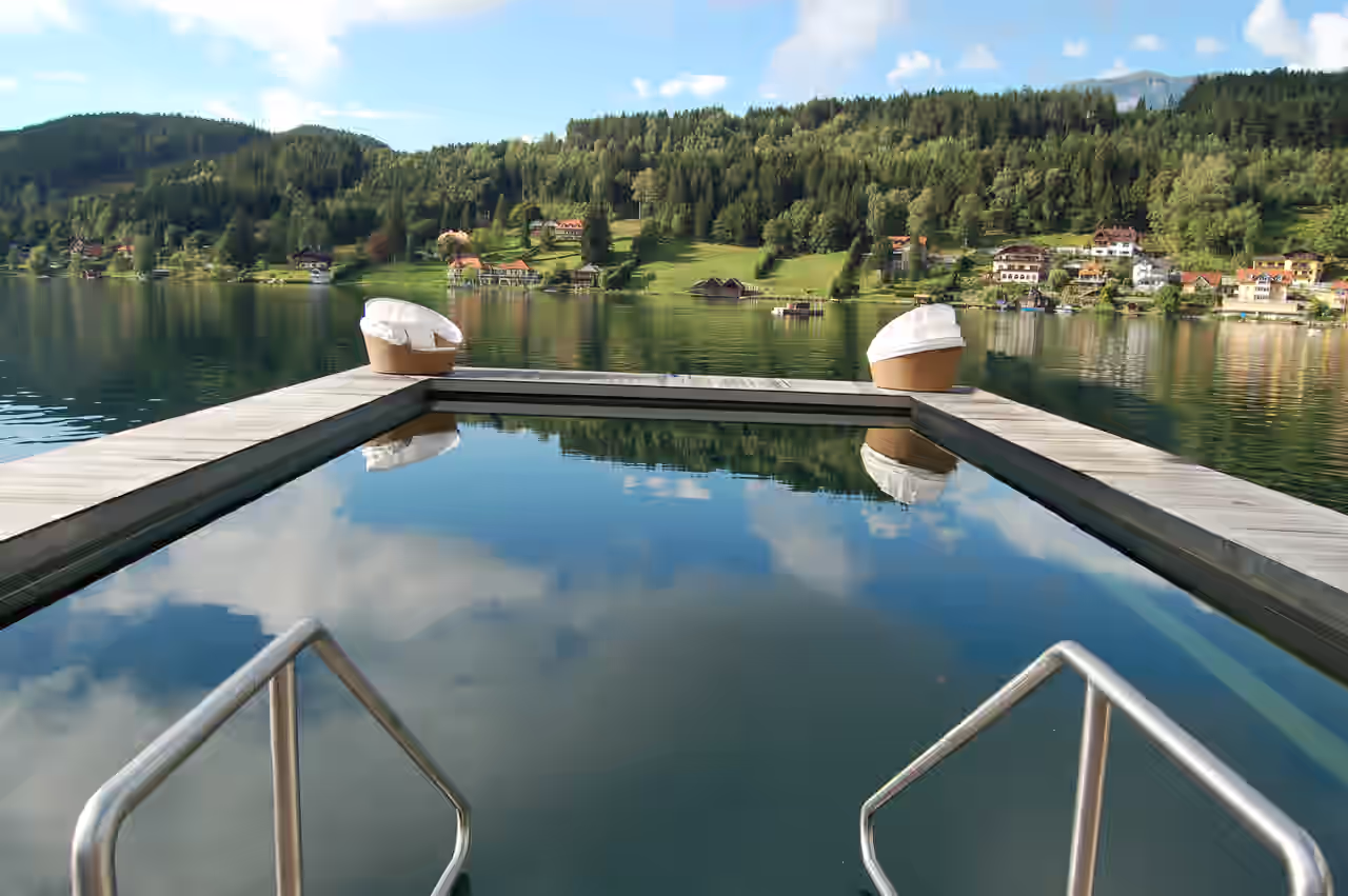 Hotel mit Infinity Pool am See in Bayern, im Hintergrund Berglandschaft