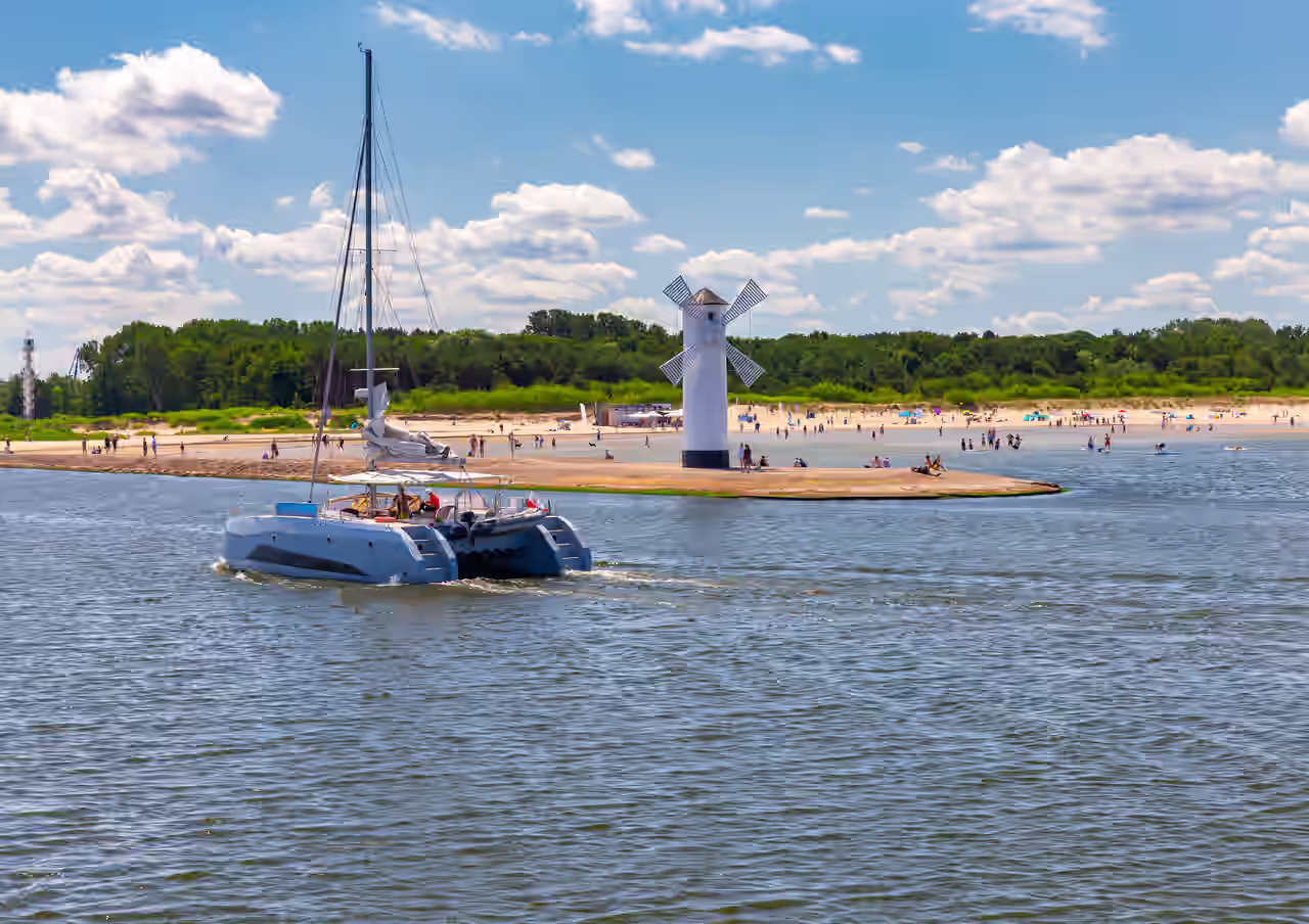 Segelkatamaran vor dem Leuchtturm am Strand von Swinemünde
