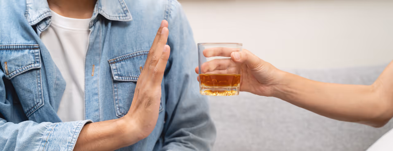 Ein Mann lehnt ein Glas mit alkoholischem Getränk ab