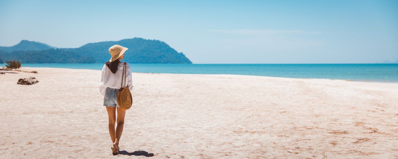 Eine Frau spaziert alleine am Strand