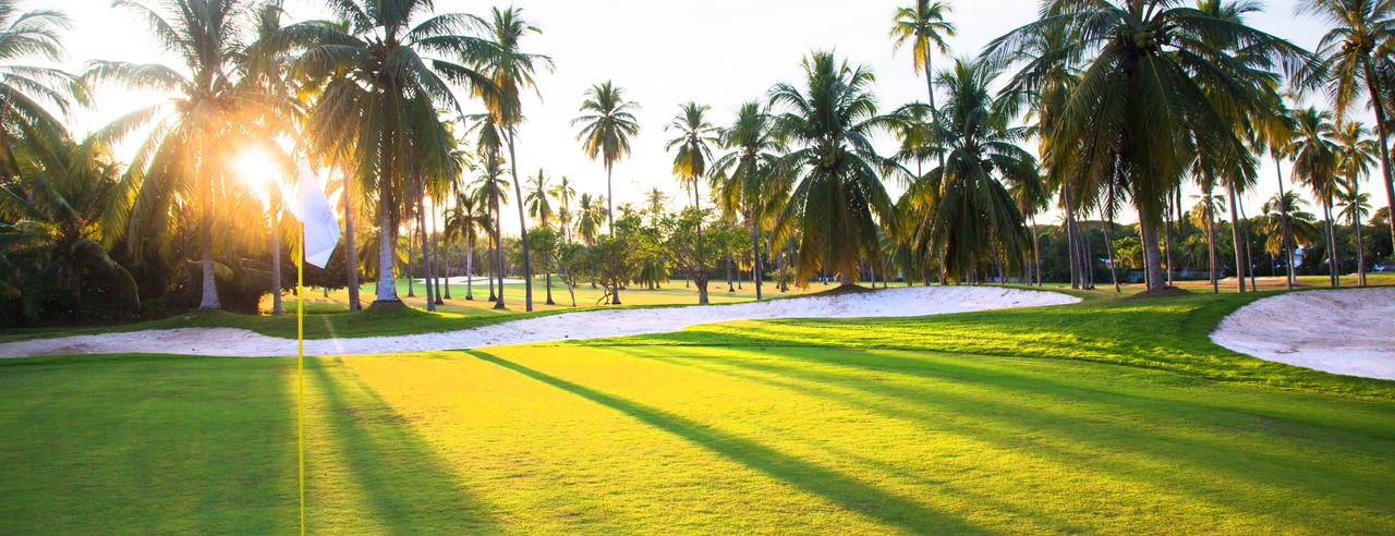 Golfplatz mit Bäumen und Hotel im Hintergrund