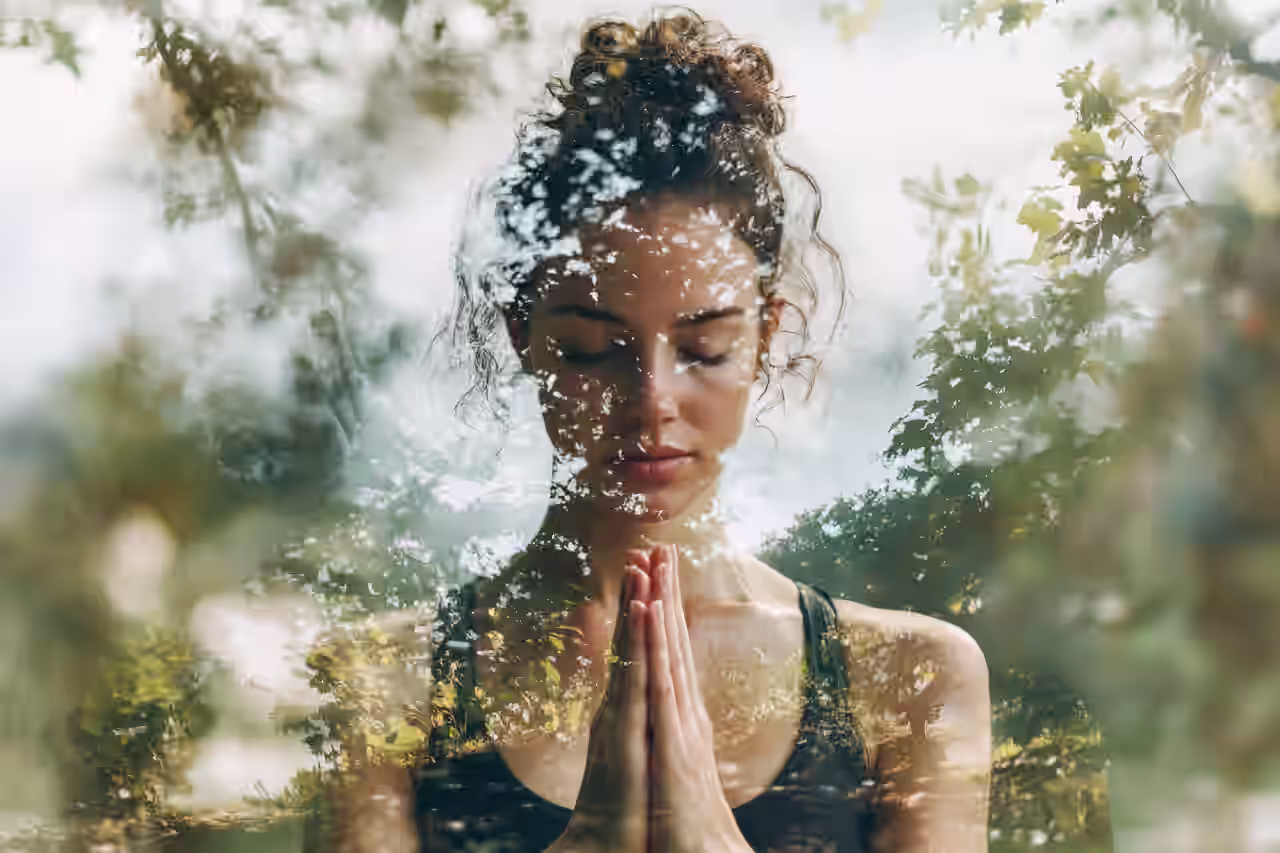 Eine Frau in Yoga Pose hat die Augen geschlossen und die Hände gefaltet