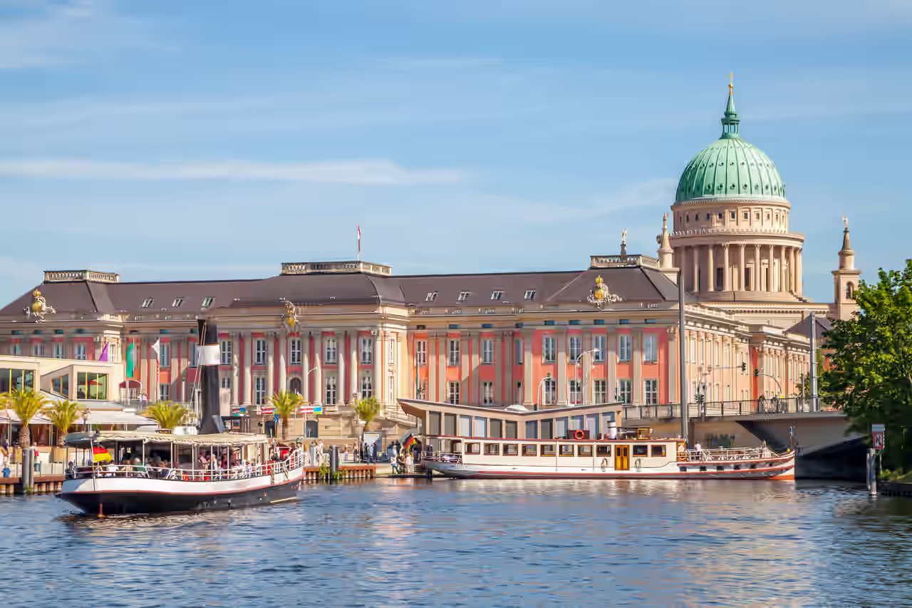 Nikolaikirche in Potsdam vom Wasser aus hinter Ausflugsschiffen im Sonnenschein