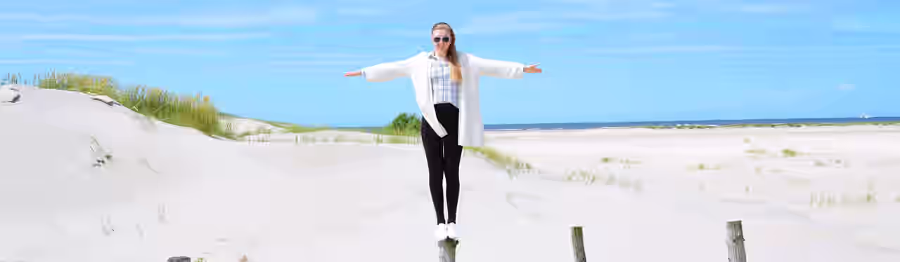 Eine Frau balanciert auf einem Pfahl am Strand