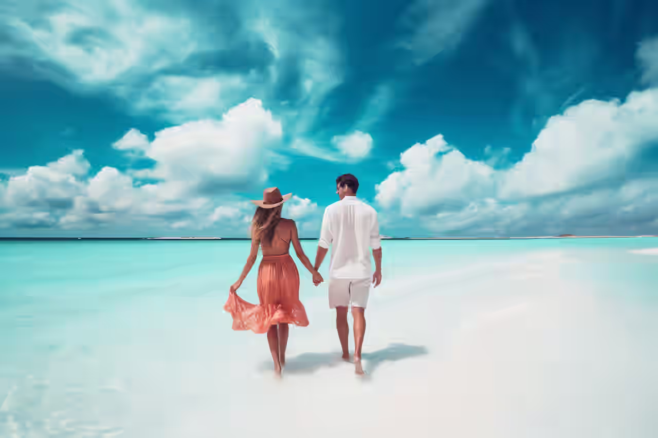 Tisch und zwei Stühle in einem Strandrestaurant mit Sandstrand und blauem Meer im Hintergrund