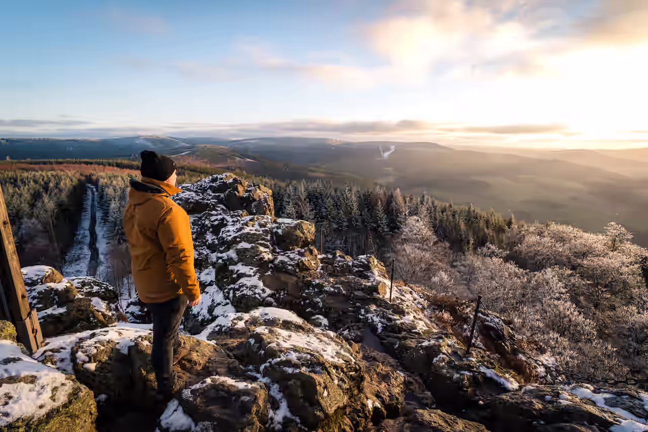 Mann mit dicker Jacke und Mütze blickt auf ein Tal im Sauerland