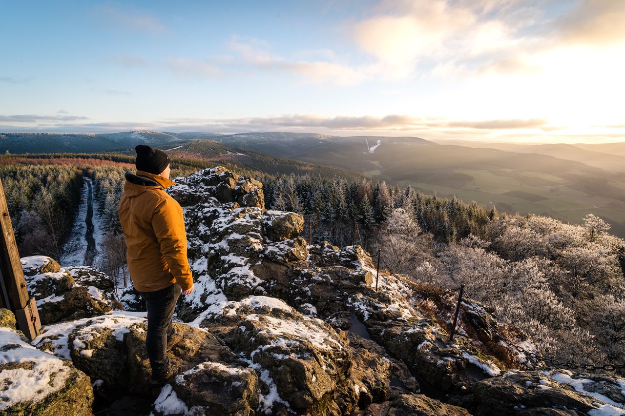 Mann mit dicker Jacke und Mütze blickt auf ein Tal im Sauerland