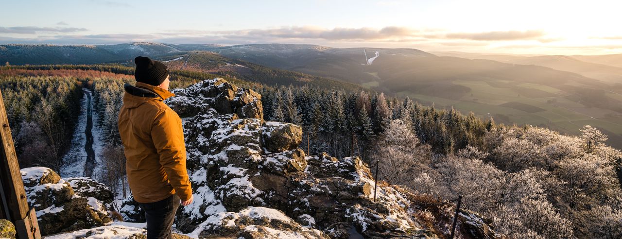 Mann mit dicker Jacke und Mütze blickt auf ein Tal im Sauerland