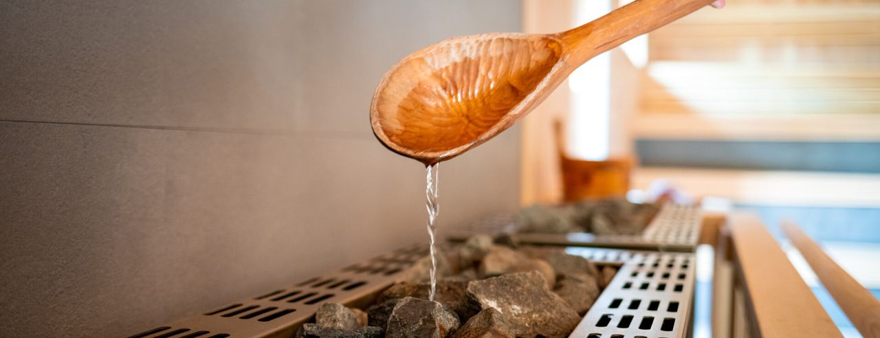 Holzlöffel mit Wasser über Saunaofen